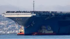 अमेरिकी विमानवाहक पोत 'यूएसएस अब्राहम लिंकन' विशाल दिखाई देता है और समुद्र के बीच खड़ा है, जिस पर अमेरिकी नौसेना और अमेरिकी सेना के जवान मौजूद हैं.