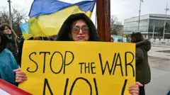 Намойишчи 2026 йил 17–18 февраль кунлари Женевада Россия, Украина ва АҚШ вакиллари ўртасидаги янги музокаралар давомида плакат кўтариб турибди.
