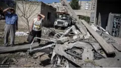 مواطنان أوكرانيان يقفان خارج مبنى للشقق السكنية دمرته ضربة صاروخية روسية في بوكروفسك بمنطقة دونيتسك