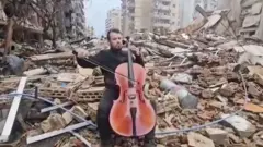 भग्नावशेषमाथि बसेर चेलो बजाउँदै महदी साहेली