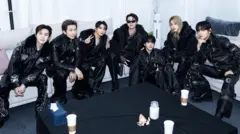 Os sete membros do BTS, vestidos de preto da cabeça aos pés, sentados ao redor de um sofá antes do show em Goyang, Coreia do Sul