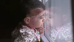 زینت نشسته و از پنجره به بیرون خیره شده است