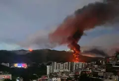 Um incêndio no Forte Tiuna, o maior complexo militar da Venezuela, é visto à distância após uma série de explosões em Caracas, em 3 de janeiro de 2026