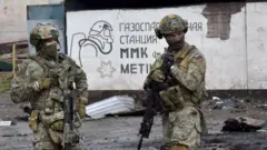 Soldados russos fazem guarda em frente à parte destruída da siderúrgica Ilyich, na cidade portuária ucraniana de Mariupol, em 18 de maio de 2022, enquanto a ofensiva militar russa continua na Ucrânia.