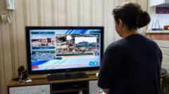 امرأة تتابع التلفزيون الحكومي الإيراني في غرفة منزلها 