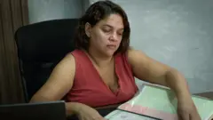 Roberta Viegas, um mulher branca, cabelos curtos, mexe em documentos