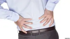 Costas de um homem colocando a mão na lombar