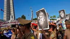 Кубинские военнослужащие несут карикатуры на президента США Дональда Трампа, проходя мимо памятника Хосе Марти во время первомайского парада на площади Революции в Гаване