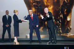 Trump pegando uma medalha. Ele está no palco ao lado do presidente da Fifa