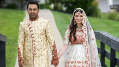 Sammi Cannold e Safi Rauf, de mãos dadas, posam para uma foto com trajes de casamento. Ela usa um vestido tradicional afegão de noiva, branco e vermelho, com lenço na cabeça; ele veste um sherwani, traje dourado típico de noivos.