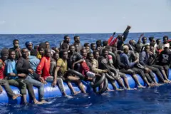 Des migrants de plusieurs nationalités différentes sont secourus par l'ONG espagnole Open Arms dans les eaux internationales, en mer le 30 septembre 2023. Ils sont assis en masse dans un canoé de fortune.