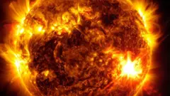 Ilustração mostrando a superfície do sol durante tempestade solar: há pontos mais claros e 'fios dourados'explosões