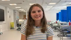 A médica Ellie Waters-Barnes sentada na enfermaria da Universidade de Keele.