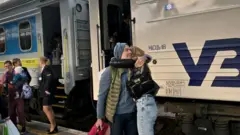 Люди на вокзалі стоять біля потяга