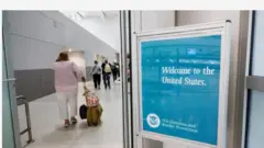 Aworan awọn arinrinajo ati patako to n ki wọn kaabọ si America