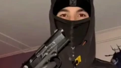فردی که سر و چهرهاش پوشیده و تنها چشمهایش معلوم است، تپانچهای را در دست گرفته رو به دوربین نشان میدهد