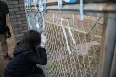 제주항공 여객기 참사 1주기를 하루 앞두고 한 여성 유가족이 사고 현장에서 철조망을 잡고 꿇어앉아 눈물을 흘리고 있다