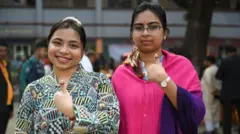 দুই জন নারী তাদের আঙুলে ভোটের অমোচনীয় কালি দেখাচ্ছেন, তাদের মুখে হাসি