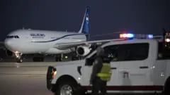 Um agente alfandegário observa o avião que transportava a seleção iraniana de futebol durante o pouso no Aeroporto Internacional de Tijuana, no México, em 7 de junho de 2026, antes do início da Copa do Mundo de 2026.