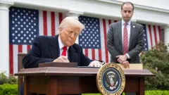 책상에 앉아 서명 중인 트럼프 대통령