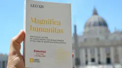 Exemplar da encíclica Magnifica Humanitas, do papa Leão 14. Ao fundo, aparece a Basílica de São Pedro, no Vaticano