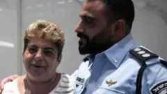 راکل ادری از اوفاغیم در جنوب اسرائیل، که توسط گروه مبارز فلسطینی حماس به گروگان گرفته شده بود، با دورون آلموگ، رئیس آژانس یهود، در دیدار با رئیس‌جمهور ایالات متحده آمریکا در تل آویو در ۱۸ اکتبر ۲۰۲۳، عکس می‌گیرد. 