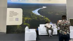 Um homem negro tira foto de outro homem negro que está sentado em uma poltrona