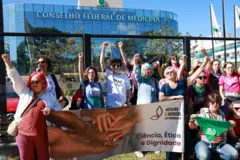 Mulheres protestando com cartazesjoguinho de ganhar dinheiro grátisfrente a prédio do CFM