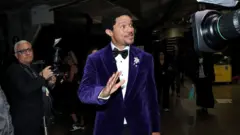 Trevor Noah wear purple suit for di Grammys. 
