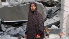 Uma mulher palestina no local de um ataque israelense a uma casa em Khan Younis, no sul da Faixa de Gaza (2 de abril de 2025)