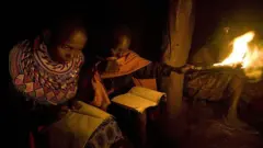 Ifoto yafashwe ku itariki ya 24 Gicurasi (5) mu 2012, igaragaza abana barimo kwiga nijoro bakoresheje umuriro wo ku giti mu nzu y’iwabo yubakishijwe ibyondo isakajwe ibyatsi, izwi nka manyatta, ahitwa i Kisima, mu karere ka Samburu, ku ntera ya kilometero hafi 350 mu majyaruguru ya Nairobi. 