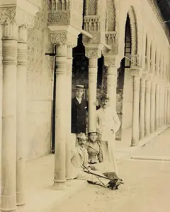 Foto de George W. Vanderbilt com amigos em Granada, na Espanha. A imagem mostra Vanderbilt, dois amigos e uma amiga, vestidos com roupas da época e chapéus, em uma antiga construção com arcos em Granada.
