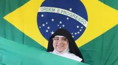 Madre Maria Rafaela, com vestes de freira, posa com bandeira do Brasil ao fundo