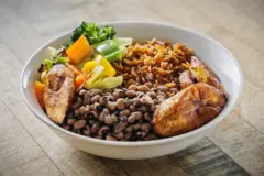 Bol de riz cuit à la tomate avec des haricots, de la banane plantain et des légumes