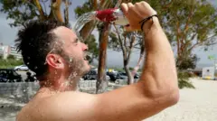 Sərinlənmək üçün üzünə su tökən turist 