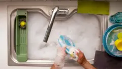 pessoa lavando louça com espuma