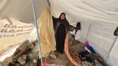 سيدة فى إحدى الخيام ترفع مرتبة نوم وأكياس بلاستيكية تظهر تحتها مياه الأمطار