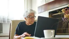 Жінка похилого віку працює за комп'ютером