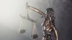 Statue symbolizing blindess of justice holds scales against the shining light.