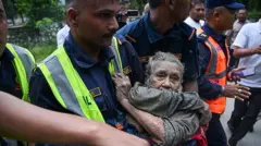Rescatistas cargan a una anciana cubierta de barro en Nepal.