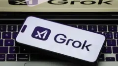 Фотография логотипа Grok на белом фоне телефона, лежащего на открытом ноутбуке, на котором также отображается логотип Grok.