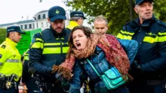 Seorang perempuan ditangkap oleh polisi dalam unjuk rasa di Amsterdam.
