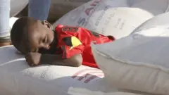 টিগ্রে অঞ্চলে এক শিশু খাদ্যের বস্তার ওপর শুয়ে আছে।