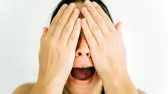 Жінка кричить, закривши обличчя руками - стокове фото