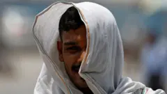 Un homme se couvre d'un tissu pour se protéger de la chaleur lors d'une chaude journée d'été à New Delhi, en Inde, le 20 mai 2024. 