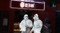 Relawan tenaga kesehatan memakai APD saat berjalan di Stasiun Kereta Api Beijing Barat, pada 15 Desember 2022.