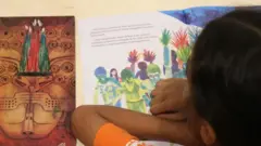 Criança lendo um livro durante mostra sobre literatura indígena
