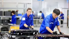 Operários trabalham em fábrica de baterias