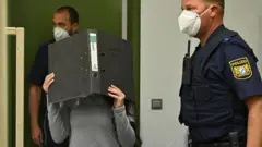 جنیفر وینیسچ په محکمه کې خپل مخ په دوتنه کې پټ کړی