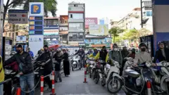 Pengemudi antre untuk mengisi bahan bakar ke kendaraan mereka di sebuah stasiun pengisian bahan bakar di Hanoi, Selasa (10/03). Vietnam mengumumkan pada 9 Maret bahwa mereka akan menghapus tarif impor bahan bakar, karena perang antara AS dan Israel dengan Iran mengganggu pasokan minyak dan mendorong harga ke level tertinggi sejak 2022.